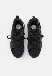 Black athletic shoes with mesh and synthetic upper, round laces, cushioned collar, and textured sole featuring a distinct pattern.