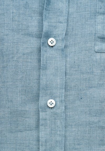 Ανοιχτό μπλε λινό πουκάμισο με υφή, διαθέτει λευκά κουμπιά και τσέπη στην αριστερή πλευρά.