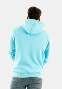 Sweat-shirt à capuche bleu clair avec une texture douce, poche kangourou, poignets et ourlet côtelés, vu de dos.