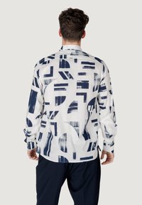 Witte langemouwen shirt met abstracte blauwe patronen. Gemaakt van lichtgewicht stof met een kraag en knoopmanchetten.