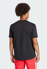 Zwarte katoenen T-shirt met korte mouwen, ronde hals en een relaxte pasvorm, gezien van achteren. Geen zichtbare patronen of logo's.