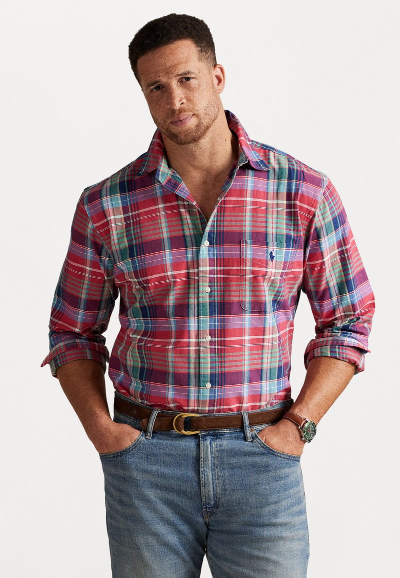 Sarkans un zils šallēts krekls ar garām piedurknēm, pogājamais dizains, krūšu kabata un apkakle, saskaņots ar džinsiem un brūnu jostu.