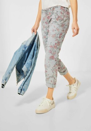Jeans gris clair à motif floral avec des ourlets retroussés, associés à une veste en denim et des baskets blanches. Tissu en mélange de coton ; coupe décontractée.