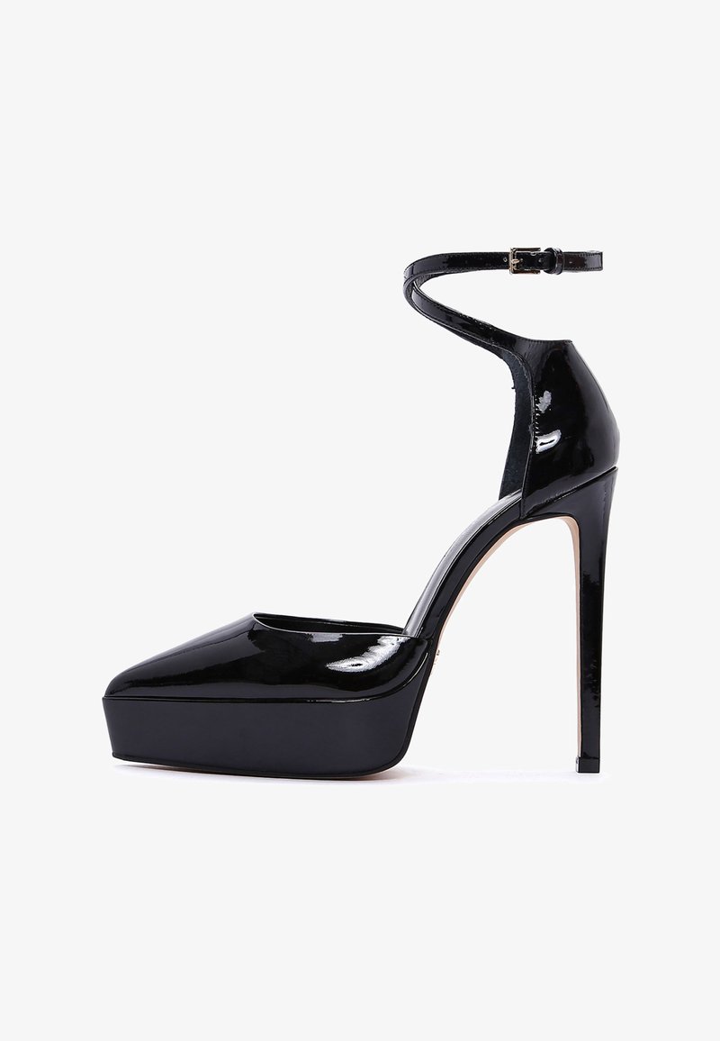 Black patent leather platform heels with a pointed toe, ankle strap, and stiletto heel; smooth texture and high-gloss finish.