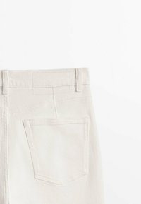 Witte denim jeans met een achterzak, gestikte details en een schoon ontwerp van de tailleband. De stof lijkt glad met een lichte textuur.