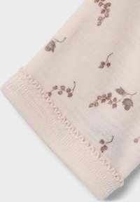 Ljusrosa tyg med ett delikat blommönster i mauve och grått. Sömmen avslutas med en subtil virkad detalj.