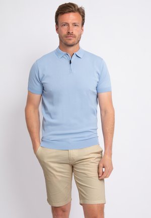 Hellblaues kurzärmliges Poloshirt mit Reißverschlusskragen; kombiniert mit beigen Shorts, beide aus glattem Baumwollstoff. Lässiger Schnitt, sauberes Design.