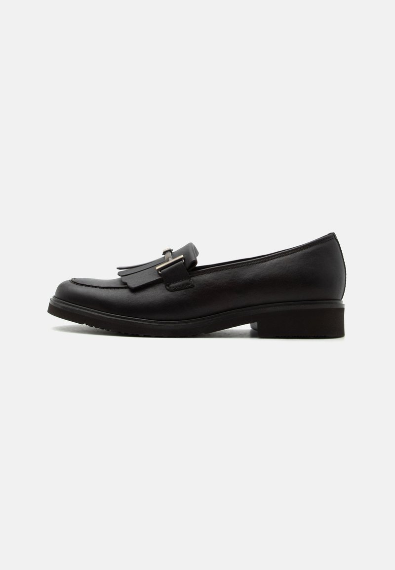 Mocassin en cuir noir avec petit talon, franges décoratives et détail de boucle argentée, vu de profil sur fond uni.