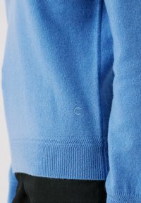 Maglione lavorato a maglia di colore azzurro chiaro con orlo e polsini a coste. Presenta un logo discreto ricamato sulla manica. Texture morbida, vestibilità rilassata.