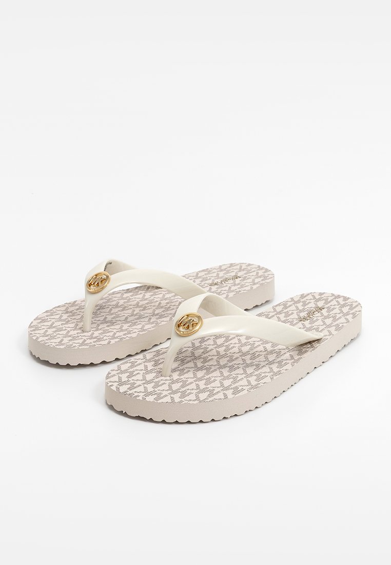 Des tongs blanches avec une semelle en beige clair texturée. Les lanières sont brillantes, avec un accent circulaire en ton doré sur chacune.