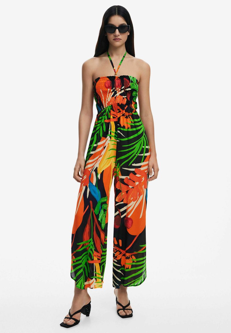 Jumpsuit colorido sin tirantes con un corsé fruncido. Presenta vibrantes patrones florales y de hojas en naranja, verde y azul sobre un fondo negro.