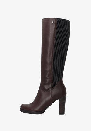 Botte haute en cuir brun avec panneau noir côtelé, talon aiguille et bout arrondi. Comprend un accent argenté près du haut.