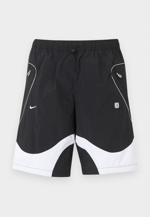 Mustavalkoiset Nike-urheilushortsit, joissa on joustava vyötärönauha, kiristysnauha, vetoketjulliset sivutaskut ja heijastavat reunukset edessä.