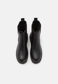 Černé kožené kotníkové boty s elastickými bočními panely, poutky na patě a robustními gumovými podrážkami. Hladký povrch a celkově elegantní design.