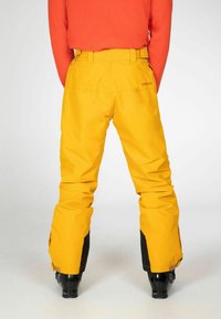 Gele skibroek met een hoge taille, riemlussen en zwarte accenten bij de boorden. Glad textuur, ontworpen voor duurzaamheid en bewegingsvrijheid.