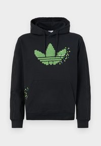 Svart hoodie med en pixelerad grön Adidas trefoil-logotyp, frontficka och ribbade ärmslut med tre ränder längs ärmarna.