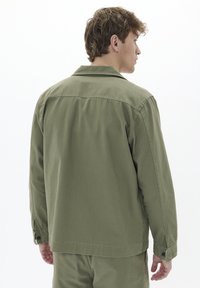 Grüne Baumwolljacke mit geradem Schnitt, knöpfbaren Ärmeln und Rückenteilnaht. Mit klassischem Kragen und Textur für einen lässigen Look.