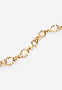 Gold chain bracelet featuring alternating oval and round links, adorned with small clear stones, polished finish, sleek design.