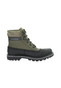 Bottes chelsea vert olive et noires avec une tige en daim, semelle en caoutchouc, design à lacets et bout renforcé. Marque Caterpillar visible.