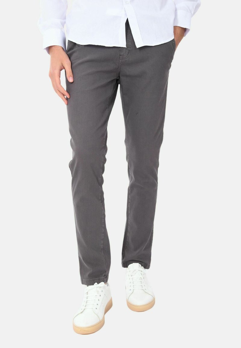 Pantaloni grigi realizzati in tessuto misto cotone, con un design aderente. Abbinati a sneaker bianche che evidenziano una suola in gomma.