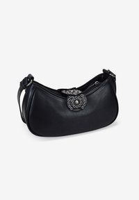 Bolso de hombro de piel negra con forma redondeada, que presenta un cierre circular decorativo adornado con ojales de metal y una perla.