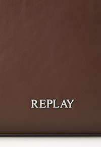 Bruine leren tas met een gladde textuur en een zilveren "REPLAY" logo. Het ontwerp is eenvoudig en rechthoekig zonder extra patronen.