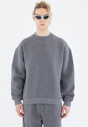 Gray sweatshirt made of cotton blend, featuring a ribbed crew neck, dropped shoulders, and a small embossed logo on the chest.