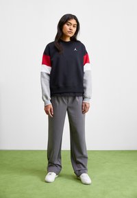 Sudadera negra con mangas en rojo, blanco y gris; pantalones anchos grises; zapatillas blancas; material de mezcla de algodón; diseño de corte relajado.