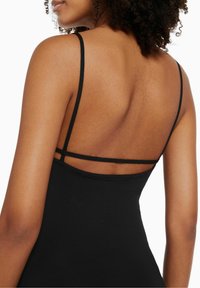 Robe noire sans manches avec des bretelles fines et un dos décolleté, confectionnée dans un tissu lisse. Détail visible de bretelle horizontale à l'arrière.