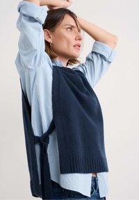 Marine gebreid sweater, gelaagd over een lichtblauw en wit gestreept shirt, met een gestrikte zijdetails en ribbelzoom. Casual pasvorm, gestructureerde materialen.