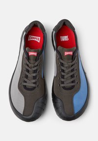 Lace-up shoes with a fabric upper in gray, blue, and dark brown. Features red branding inside and rubber outsole for traction.
