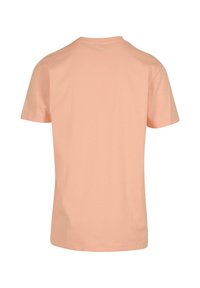 T-shirt à manches courtes en tissu pêche clair. Design col rond avec une texture lisse, sans motifs ni embellissements visibles au dos.
