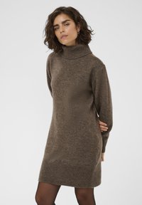 Robe en tricot marron avec un col roulé haut et des manches longues. Présente des détails côtelés aux poignets et à l'ourlet, fabriquée dans un matériau doux et texturé.