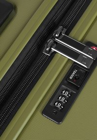 Valise texturée verte avec deux fermetures éclair noires et une serrure à combinaison avec des éléments en noir. Les accents comprennent un petit voyant lumineux.