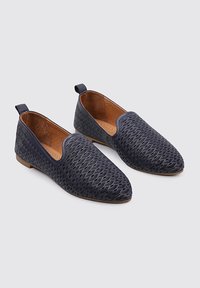 Zapatos deslizantes navy con un upper texturizado y estampado, y una suela plana y ligera. Cuenta con un interior suave y un tacón pequeño.
