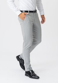 Grå tapered bukser lavet af blødt stof, med forlommer, en lynl�ås og slim fit. Båret med sorte blanke dress sko.