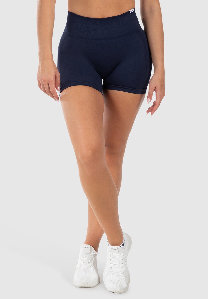 Marineblauwe high-waisted sportshorts gemaakt van elastische stof, met een gladde textuur en een passende pasvorm, getoond met witte sneakers.