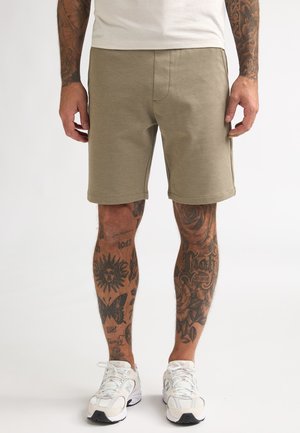 Khaki korte broek met een gladde textuur, voorzien van zakken aan de voorkant en een comfortabele pasvorm, gecombineerd met witte sportschoenen.