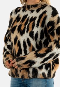 Gebreide sweater in beige, zwart en bruin met een abstract dierenprint.Heeft een hoge halslijn en lange mouwen, met een oversized pasvorm.