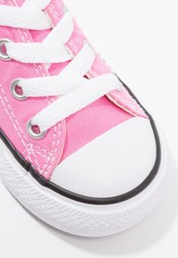 Sneaker in tela rosa con lacci bianchi, punta in gomma e suola nera. Presenta fori per i lacci e dettaglio laterale testurizzato.