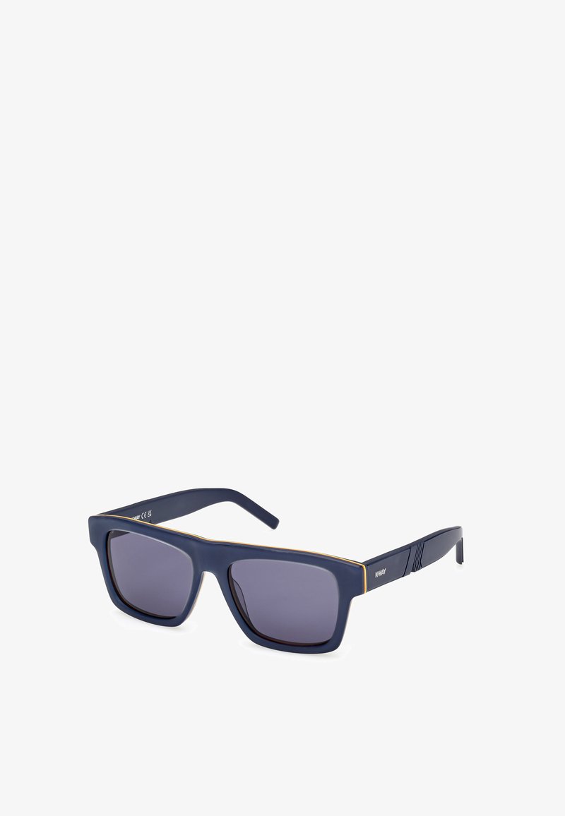 Suojalasit, joissa on tummansiniset matta kehykset, harmaansävyiset linssit ja ohuet kultaiset yksityiskohdat yläreunassa. Sivupinnoissa on tekstuuria.