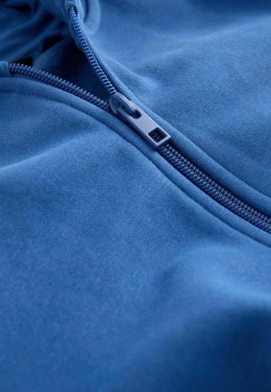 Blaues Reißverschluss-Hoodie aus glattem Stoff mit geripptem Kragen. Verfügt über einen passenden Reißverschluss mit Lasche und einer Innenauskleidung in ähnlicher Farbe.