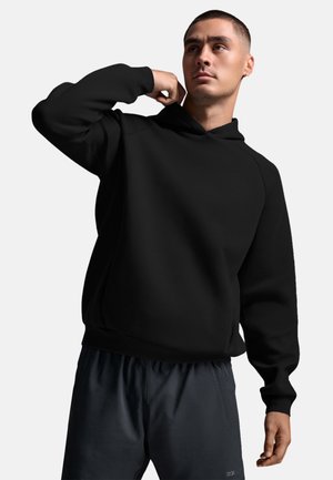 Svart hoodie med avslappnad passform, ribbade ärmslut och fåll. Slät textur, insydda ärmar, i kombination med mörka shorts.