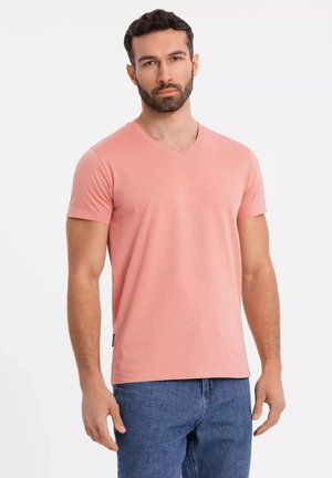 T-shirt rosa a scollo a V in un morbido misto cotone, con maniche corte e vestibilità rilassata. Indossato con jeans in denim blu.