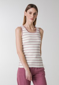 Stribet ærmeløs tanktop i creme med lyserøde striber, der har en ribbet tekstur og en rund halsudskæring. Sammen med lyserøde linnedbukser.