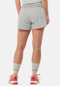 Lichtgrijze shorts van een gladde, duurzame stof met een elastische tailleband. Gepaard met koraalkleurige schoenen en grijze sokken met een patroon.