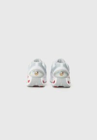 White athletic shoes with mesh upper, textured back, and red accents. Features round logo on heel and a cushioned sole for support.