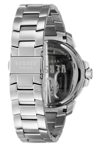 Montre en acier inoxydable avec un bracelet à maillons, finition polie et gravure "VERSUS" sur le fermoir. Le fond de boîtier transparent montre les détails.