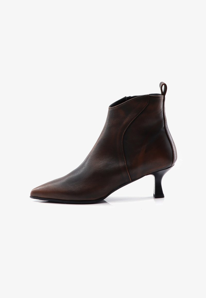 Botín de cuero marrón oscuro hasta el tobillo con punta afilada, tacón bajo tipo kitten, cremallera lateral y lengüeta en la parte posterior, exhibido sobre fondo blanco.