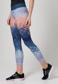 Leggings multicolores avec un dégradé allant du rose clair au bleu profond, présentant un motif éclaboussé et une large ceinture ajustée.